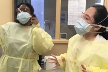 Two women in yellow scrubs sing.
