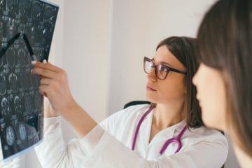 A doctor looks at brain x-rays with patient.