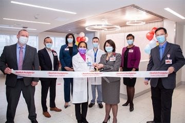 Men and women stand in front of a banner with a large pair of scissors