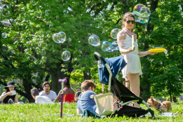 Mother blowing bubbles with child demonstrating the concept of a return to normal