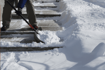 Image of a shovel moving snow on a sidewalk, to avoid back pain.