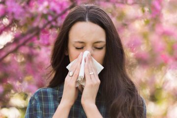 Woman blowing nose from seasonal allergies